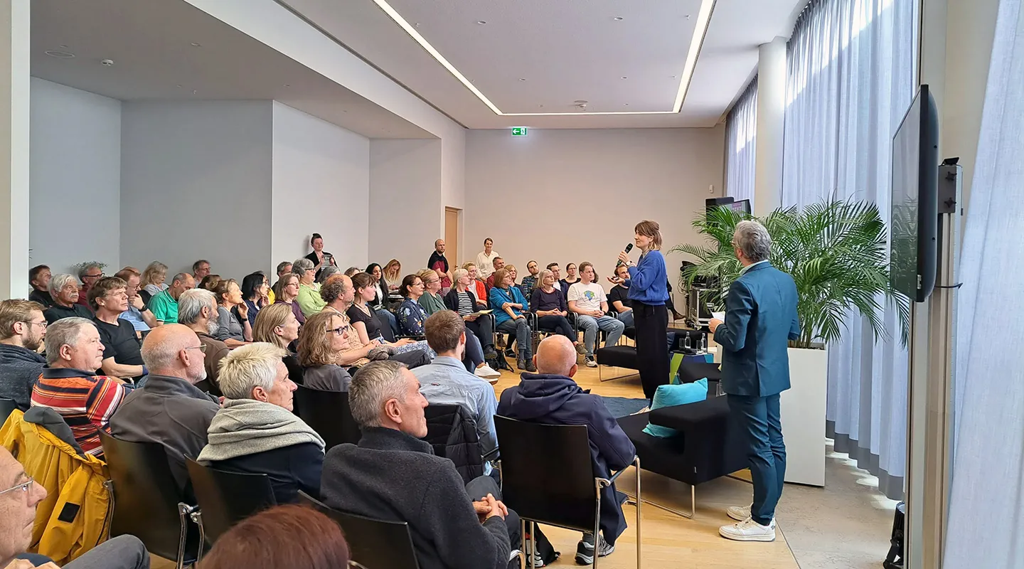 Eine Frau steht vor einer großen Gruppe von Zuhörenden