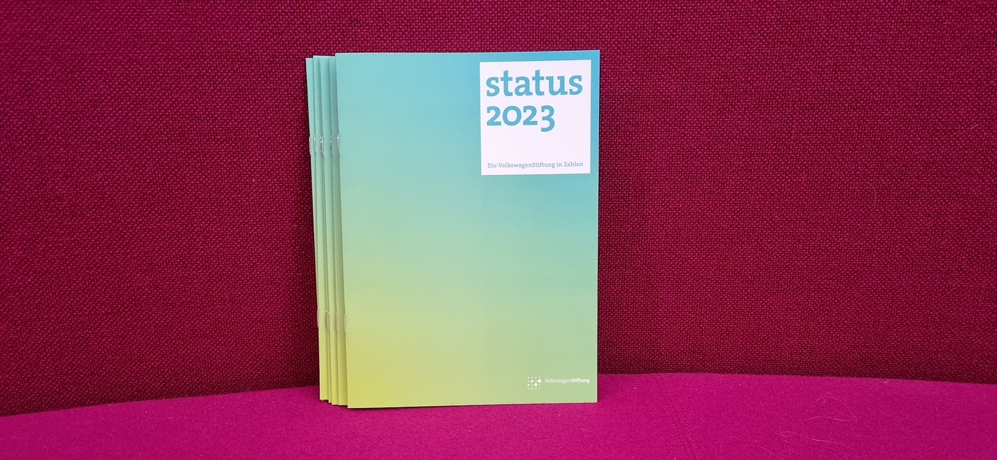 Broschüre mit Aufdruck "status 2023" vor rotem Hintergrund